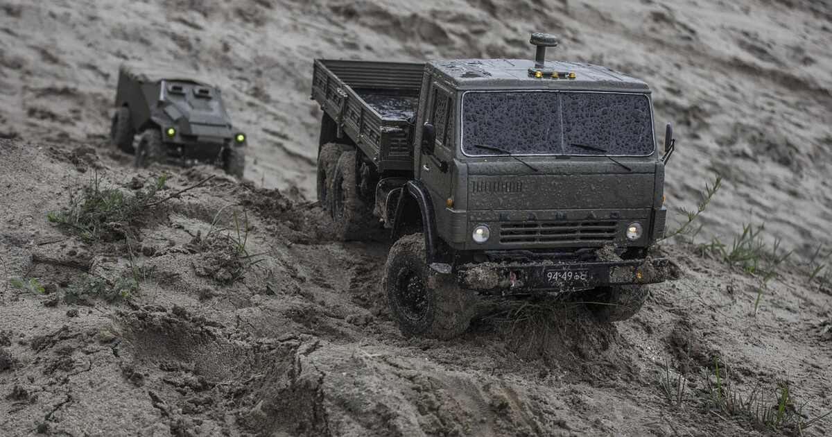 An RC truck and car on a sandy beach.